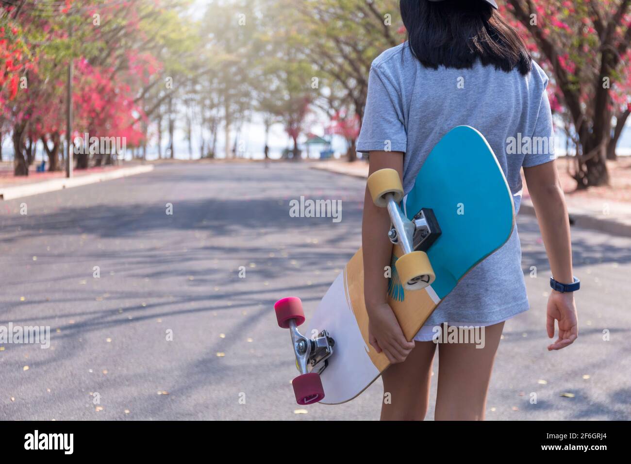 Young girl hand hold skateboard surf skate on public road park