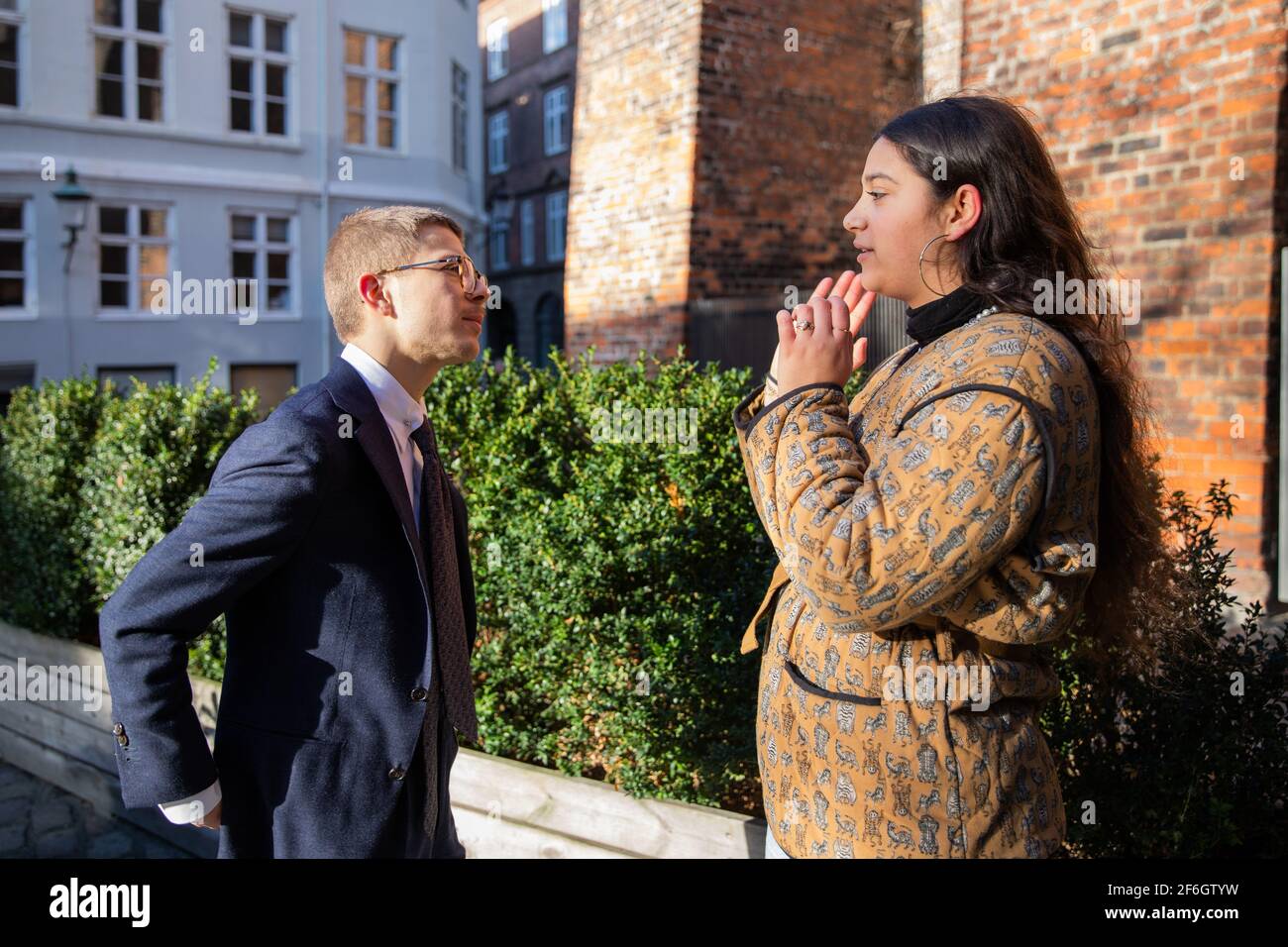 Two colleagues, man and woman discuss over a working project outdoors. Stock Photo