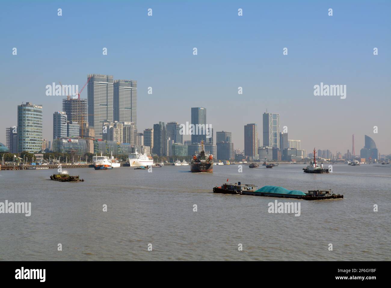 Large variety of shipping on the Huangpu river in Shanghai. Barges carry cargo and tour boats bring tourists in to the city. Stock Photo