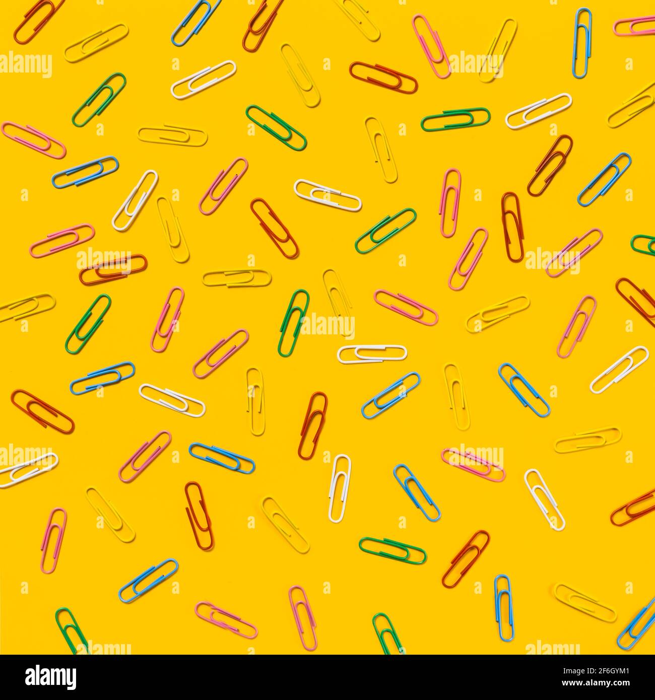 Multi colored paper clips scattered against yellow background Stock ...