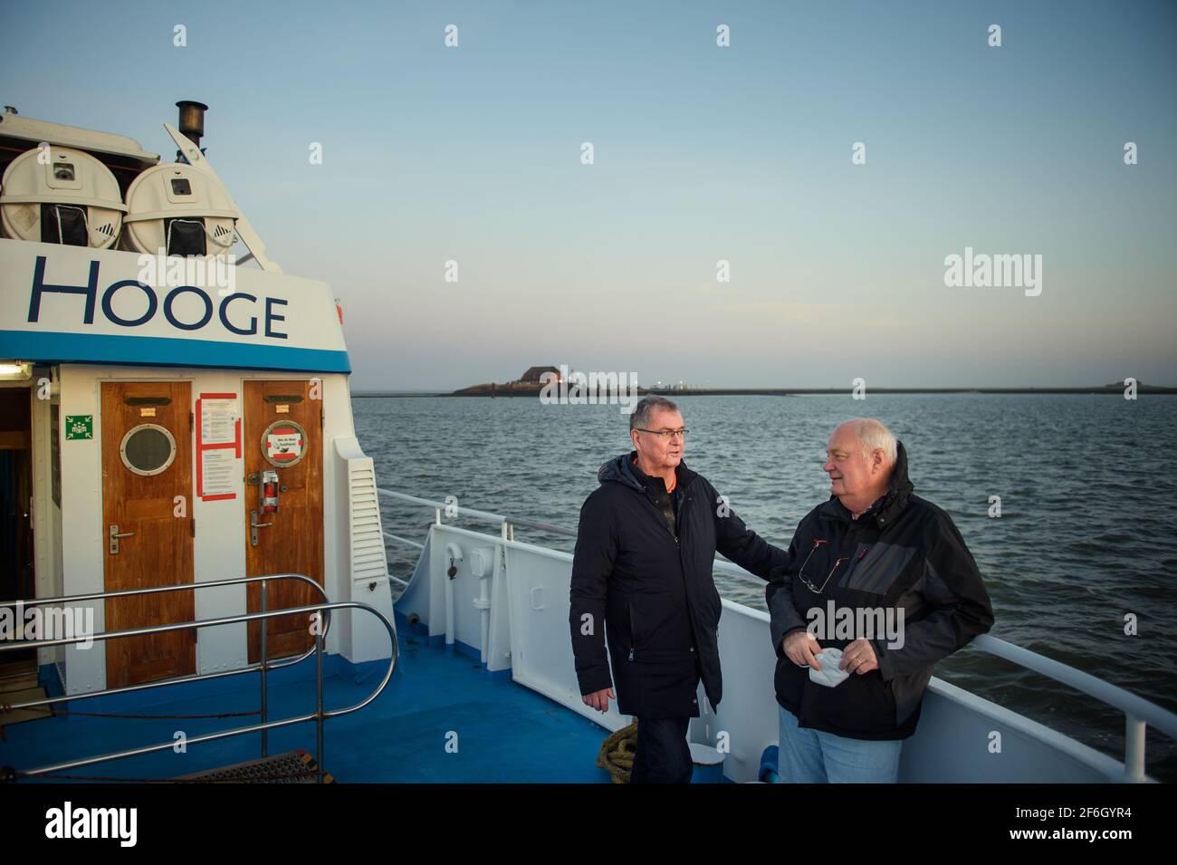 Hooge, Germany. 30th Mar, 2021. Urs Philipzig (l), medical doctor from Bredstedt and new doctor of Hallig Hooge, and Gerhard Steinort, medical doctor in Langenhorn and former doctor of Hallig Hooge, stand during sunrise at the stern of the MS Seeadler on the way to Hallig Hooge. (to dpa 'Hooge's Hallig doctor retires') Credit: Gregor Fischer/dpa/Alamy Live News Stock Photo