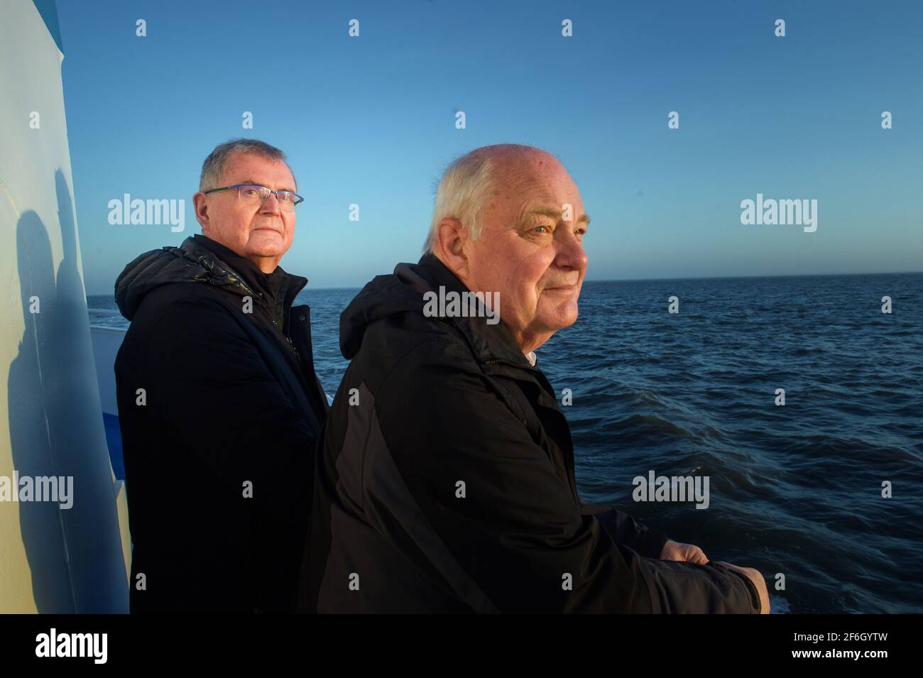 Hooge, Germany. 30th Mar, 2021. Urs Philipzig (l), medical doctor from Bredstedt and new doctor of Hallig Hooge, and Gerhard Steinort (r), medical doctor in Langenhorn and former doctor of Hallig Hooge, stand at the stern of the MS Seeadler on the way to Hallig Hooge during sunrise. (to dpa 'Hooge's Hallig doctor retires') Credit: Gregor Fischer/dpa/Alamy Live News Stock Photo