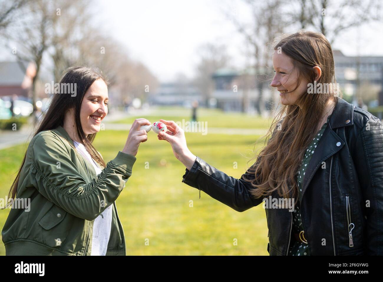 Aurich, Germany. 24th Mar, 2021. East Frisians Doreen Antkowiak (l) and  Deike Bruedigam bang Easter eggs against each other in a game of  "Hicken-Bicken". The winner is the one whose egg breaks