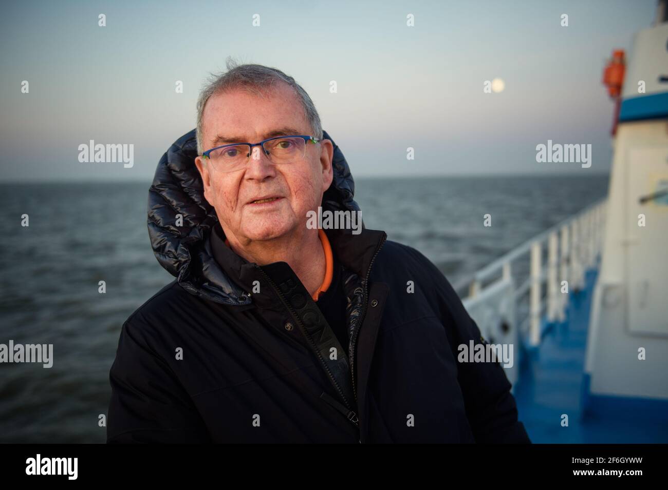 Hooge, Germany. 30th Mar, 2021. Urs Philipzig, physician from Bredstedt and new doctor of Hallig Hooge, stands at the stern of the MS Seeadler on the way to Hallig Hooge during sunrise. (to dpa 'Hooge's Hallig doctor retires') Credit: Gregor Fischer/dpa/Alamy Live News Stock Photo