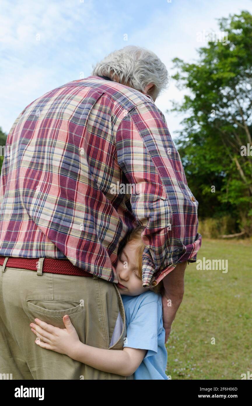 Rear view of grandfather embracing grandson (6-7) outdoors Stock Photo