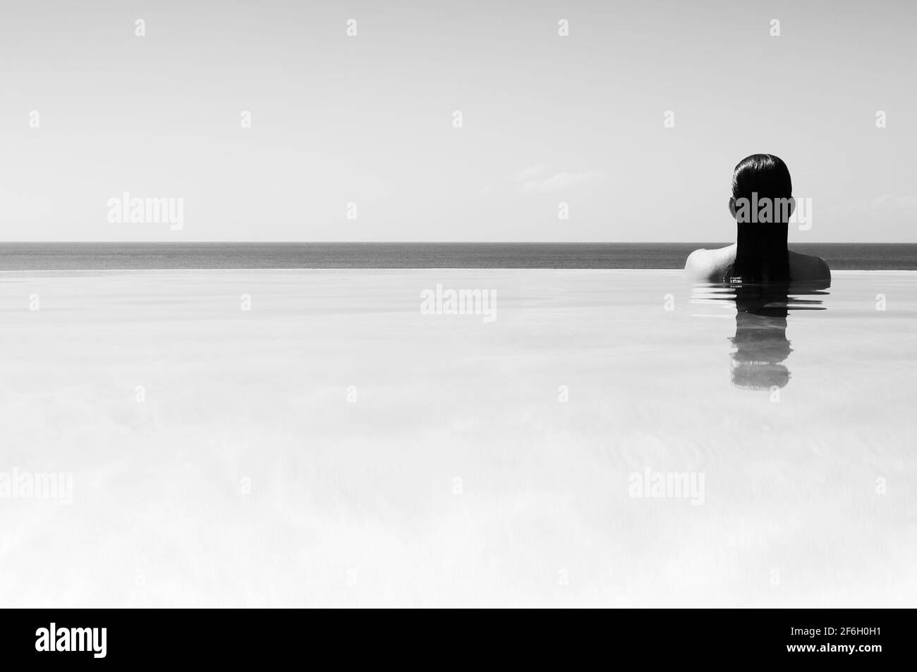 Rear view of woman in infinity pool Stock Photo