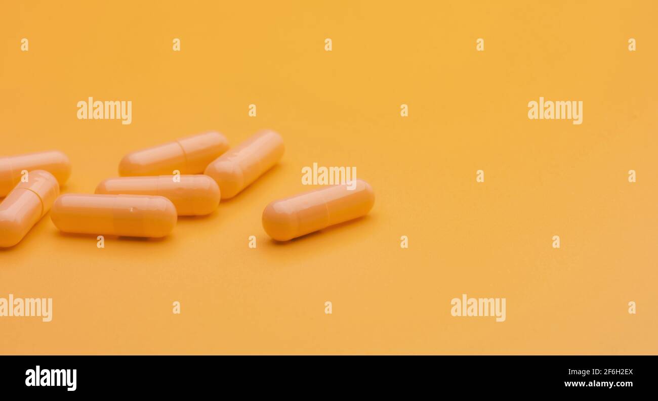 Yellow capsule pills on yellow background with copy space. Pharmacy and health insurance concept