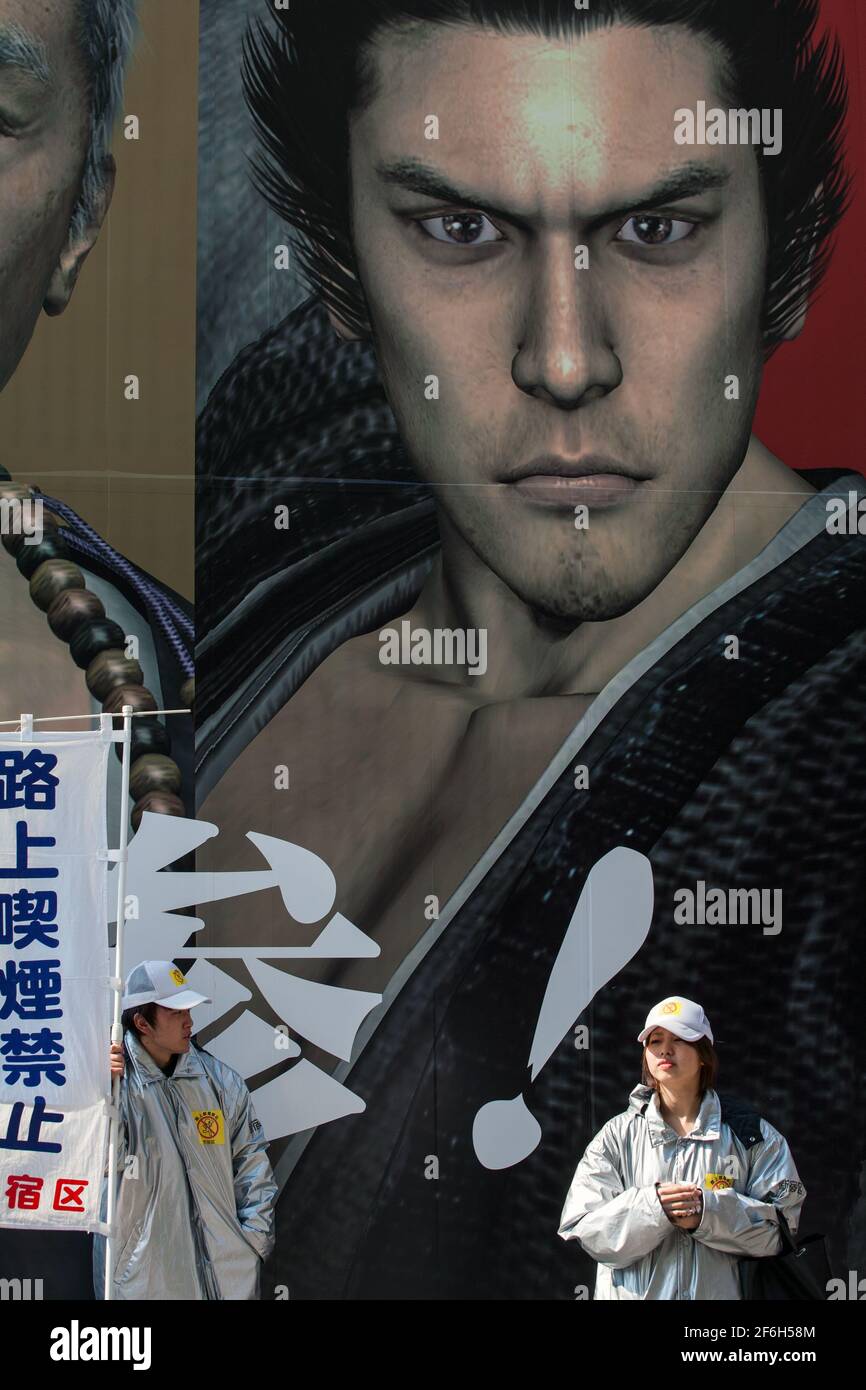 Male and female human billboards advertising in front of huge film poster, Shinjuku, Tokyo, Japan Stock Photo