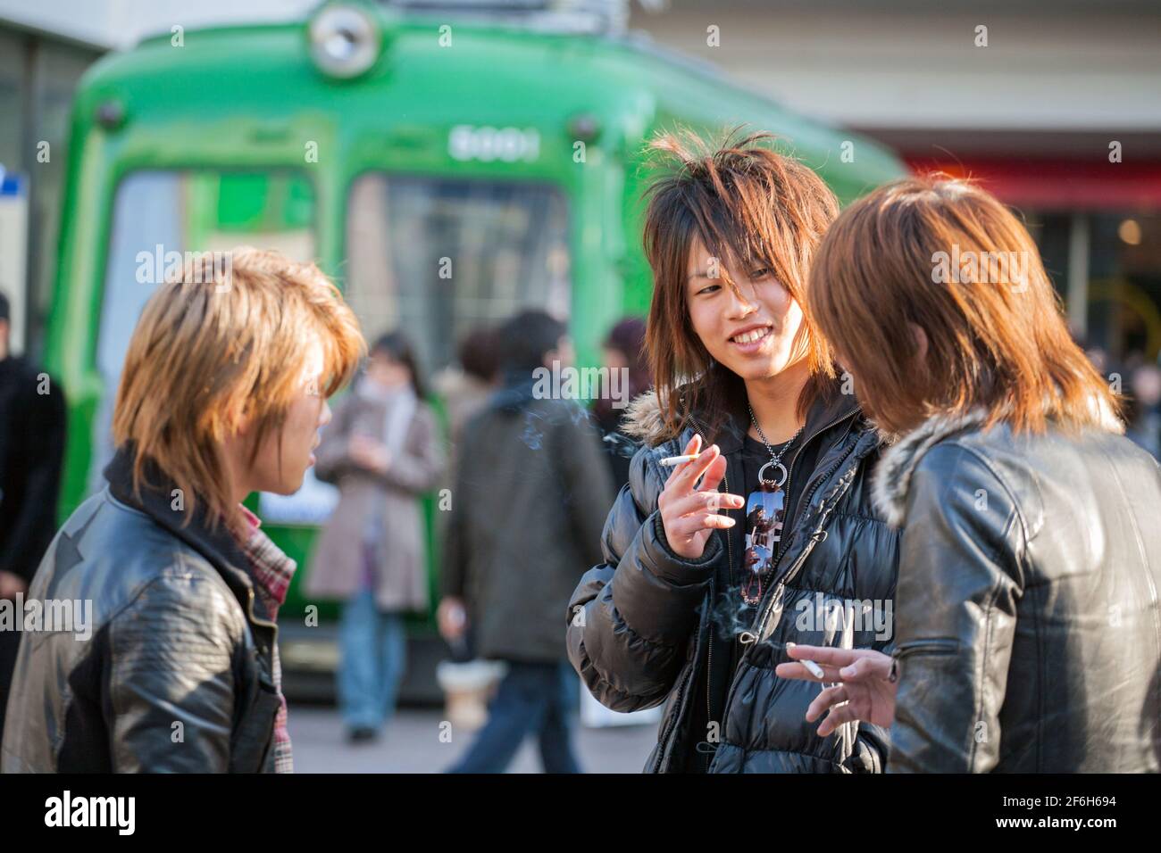 Japanese male hosts smoking cigarettes, waiting for female victims to snare back to their host club outside Shibuya JR train station, Tokyo, Japan Stock Photo