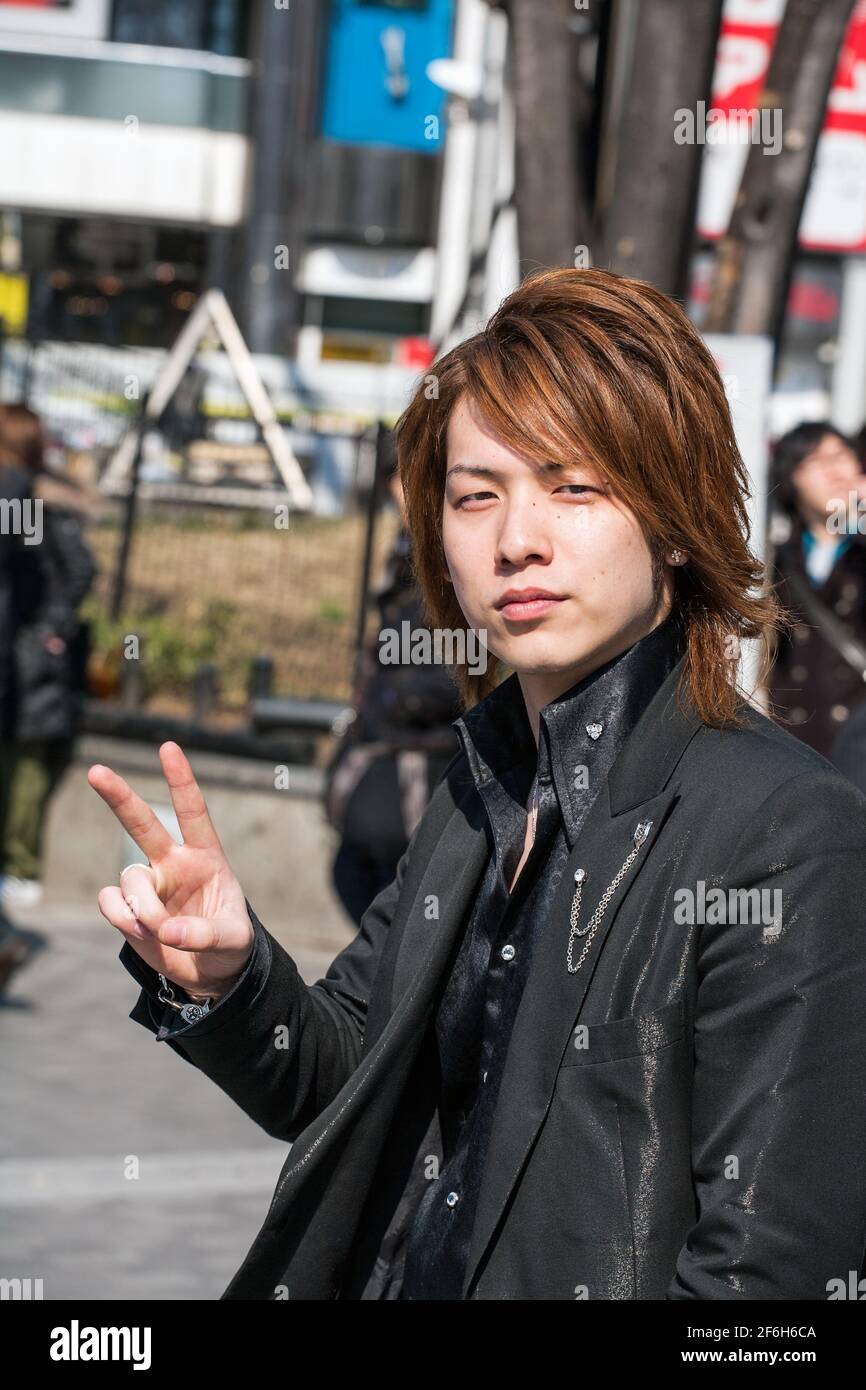 Close up of Japanese male host dressed like a rockstar wearing black clothing hanging outside Shinjuku JR train station, Tokyo, Japan Stock Photo