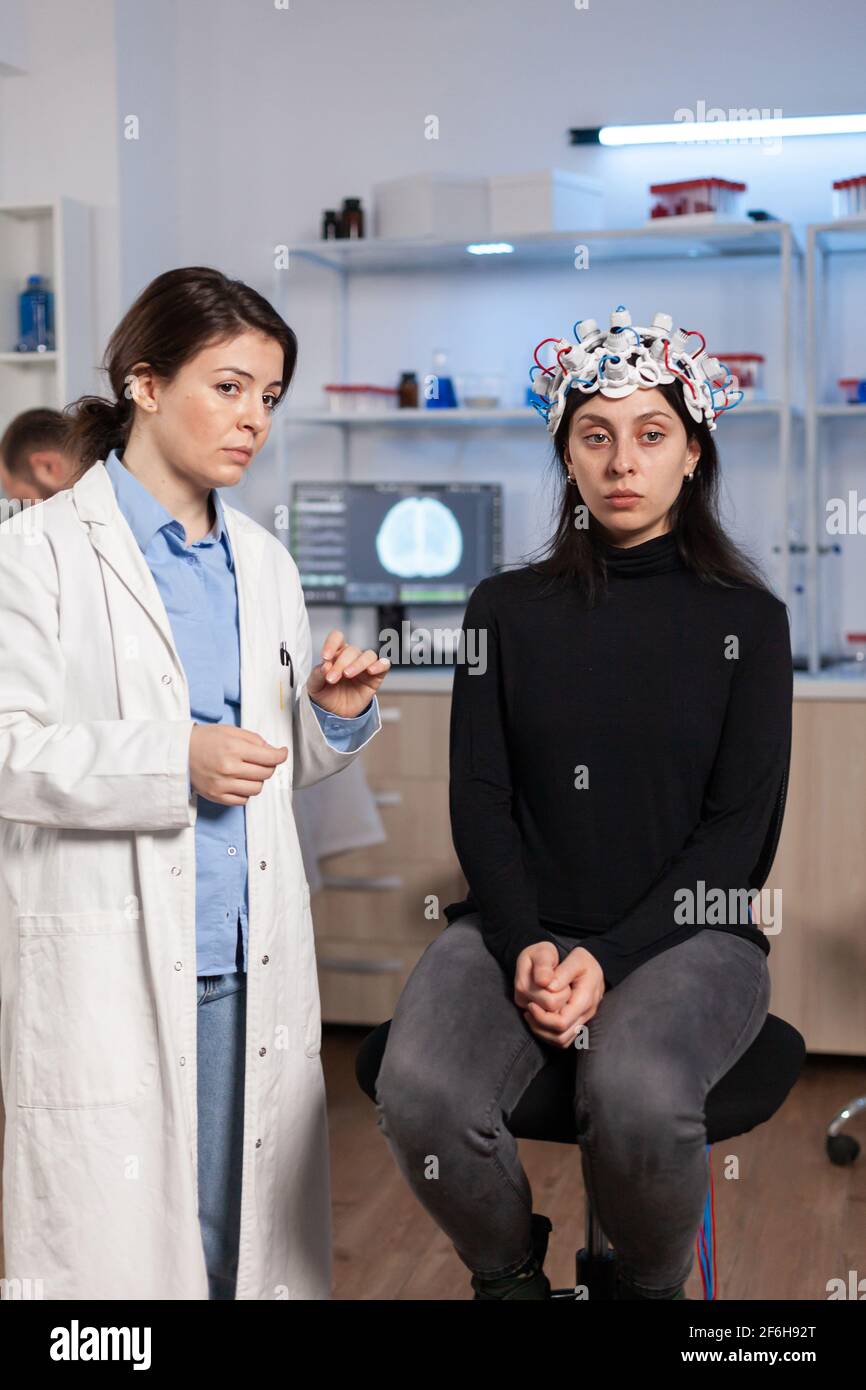 Female patient who is in a neurology clinic and her brain is being scanned. Woman sitting in lab equipped for development of experiments. Neuroscientist looking for brain trauma, nervous system. Stock Photo