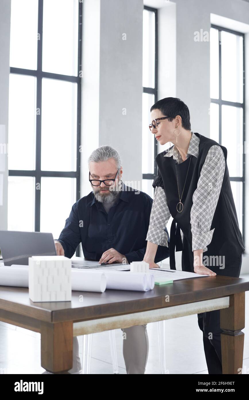 Two architects discussing project and blueprint at the table working in team at office Stock Photo