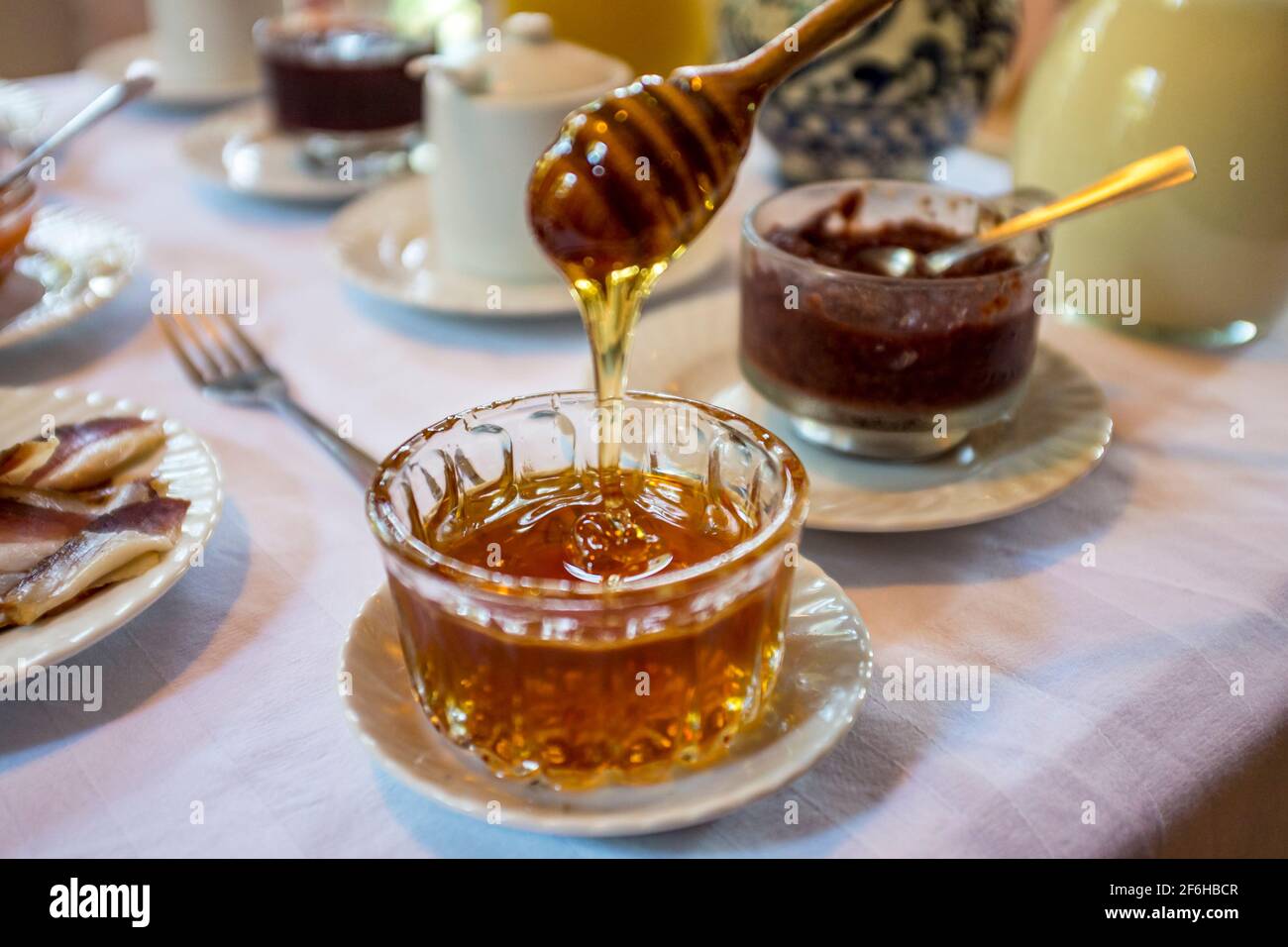 A honey dipper getting honey out of a glass jar as served for breakfast in rural Transylvania Stock Photo