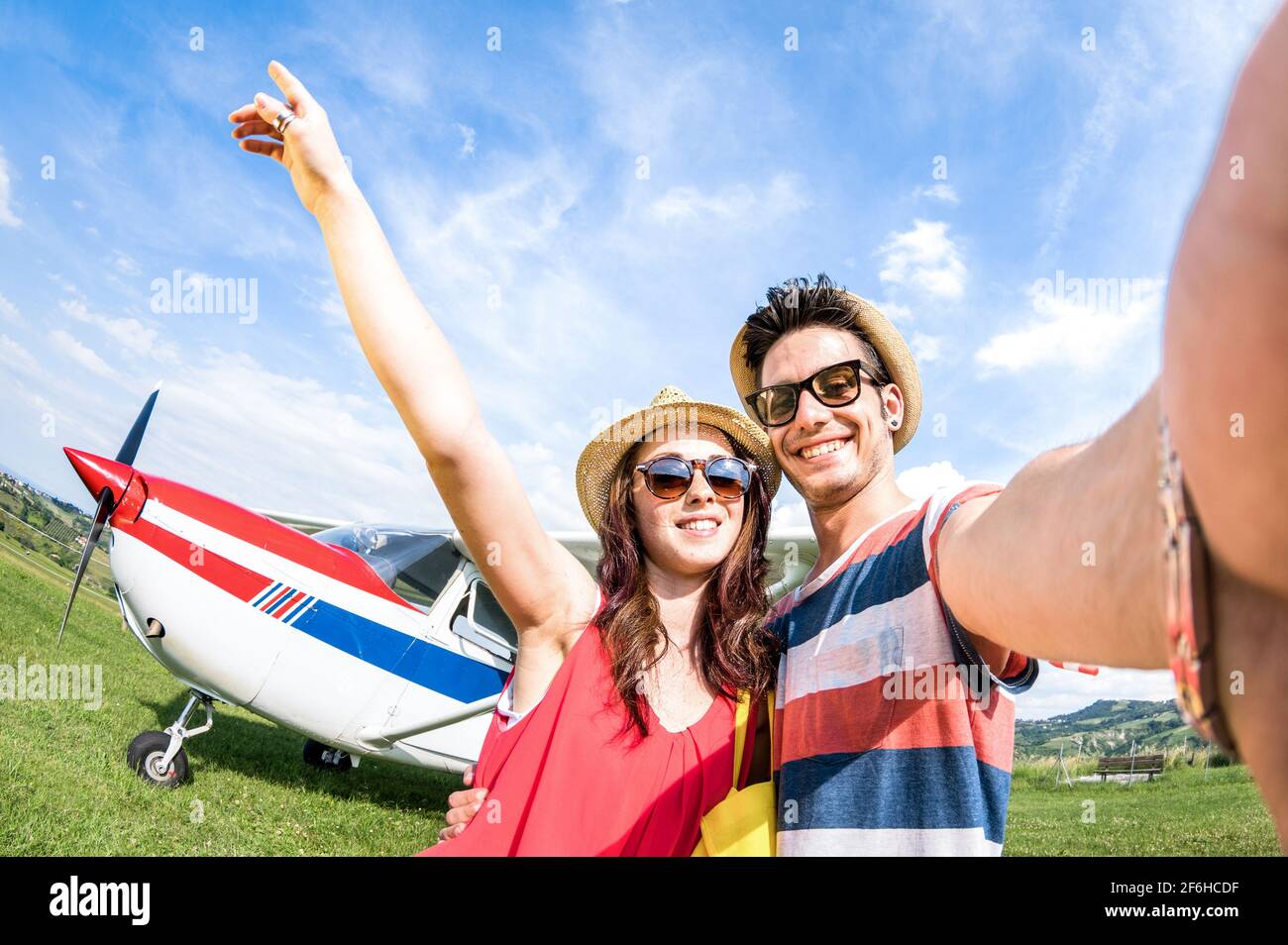 Young couple taking selfie with lightweight airplane - Happy people boarding on excursion air plane - Alternative adventure vacation concept Stock Photo