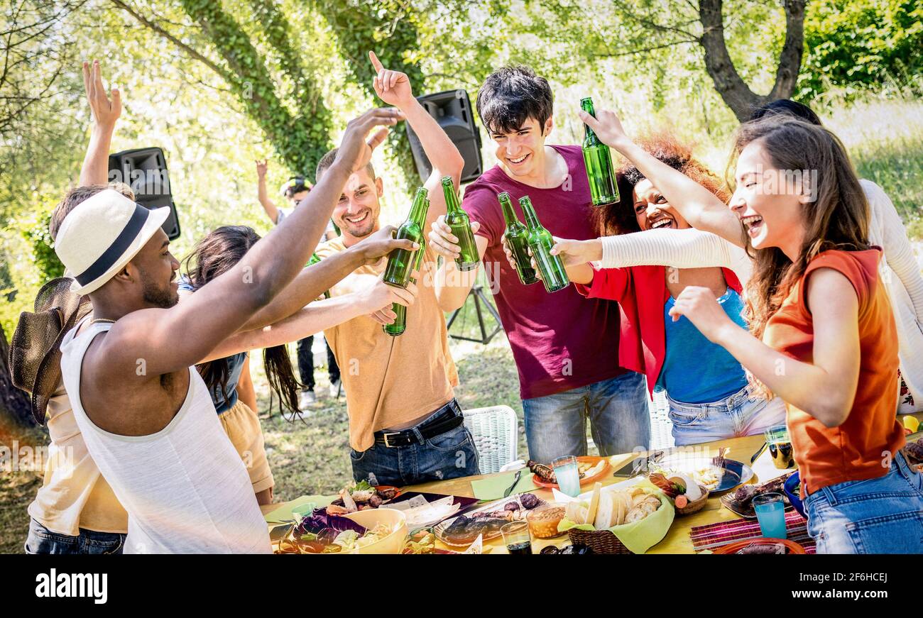 Young multiracial friends toasting beer at barbecue garden party - Friendship concept with happy people having fun at backyard summer camp Stock Photo