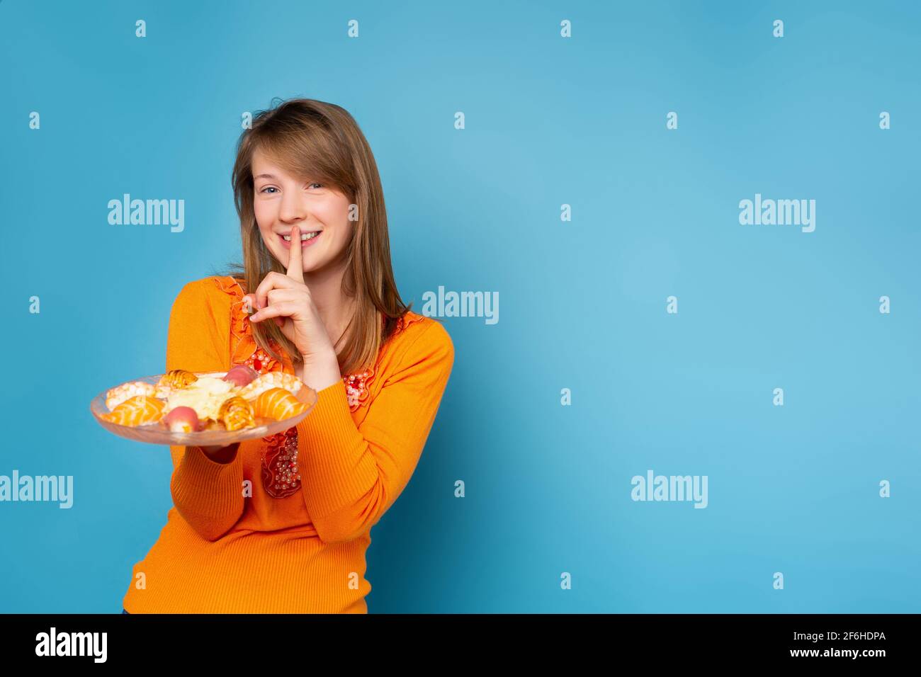 Young beautiful woman with blonde straight hair holding plate with fresh sushi cover mouth with finger, hush expression, shocked with shame for Stock Photo