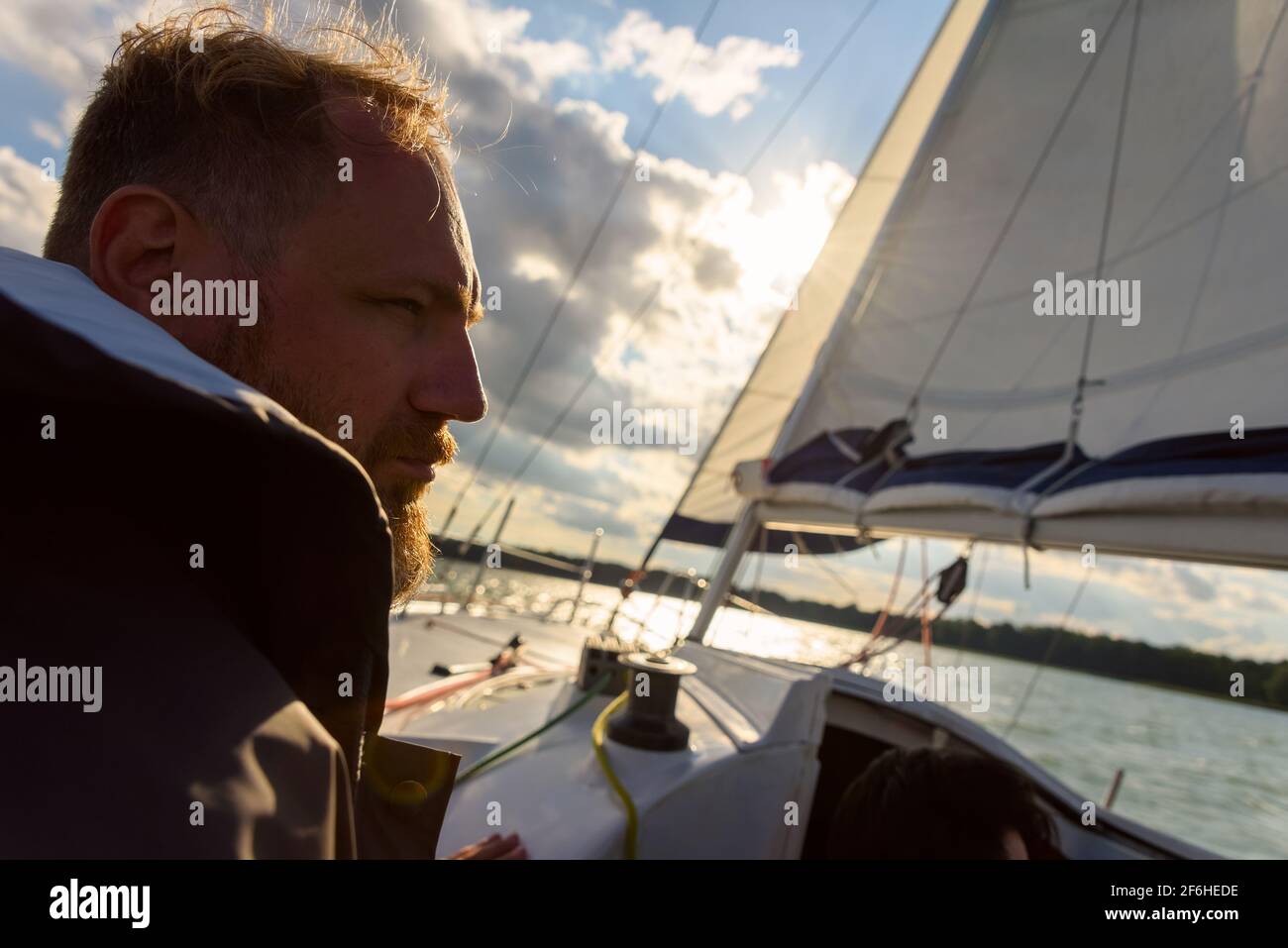 silhouette of adult bearded man portrait in sunset light sailing on a sailboat during sailing. Summer vacation Stock Photo