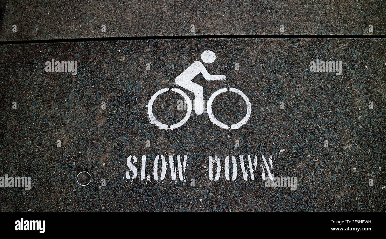 Slow Down Bicycle sign painted on concrete pavement on the Brisbane river walk Stock Photo