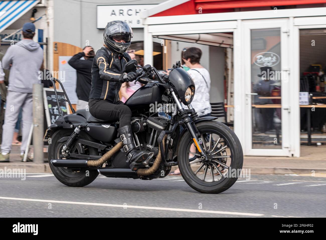 Female rider riding a Harley Davidson motorcycle in Southend on Sea Essex UK. Passing arches restaurants on Western Esplanade. Black clothing Stock Photo Alamy