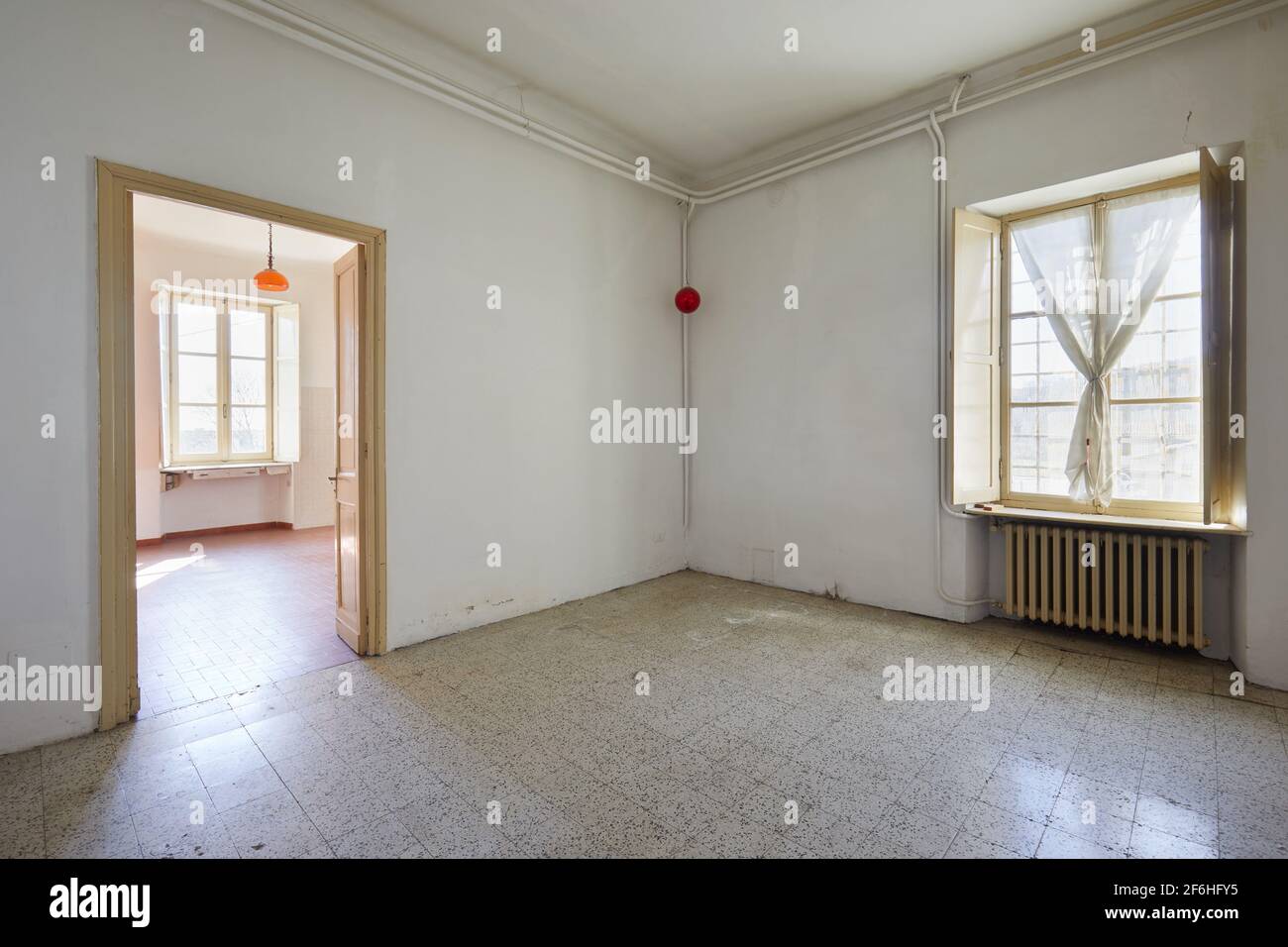 Old, empty room with tiled floor and window, sunlight Stock Photo