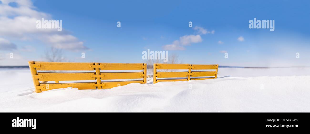 Vintage wooden Bench Painted yellow, rungs snow covered and in deep snow. Copyspace for Street Billboard placards texture background. Stock Photo