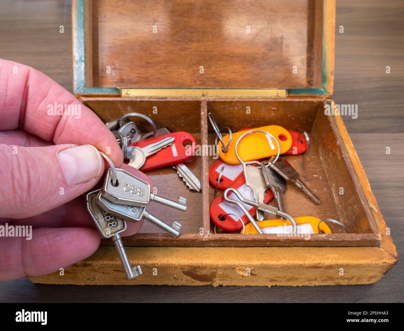 Closeup POV shot of a man's hand taking three old keys on a ring from the  many inside a tatty and worn old leather covered wooden box Stock Photo -  Alamy