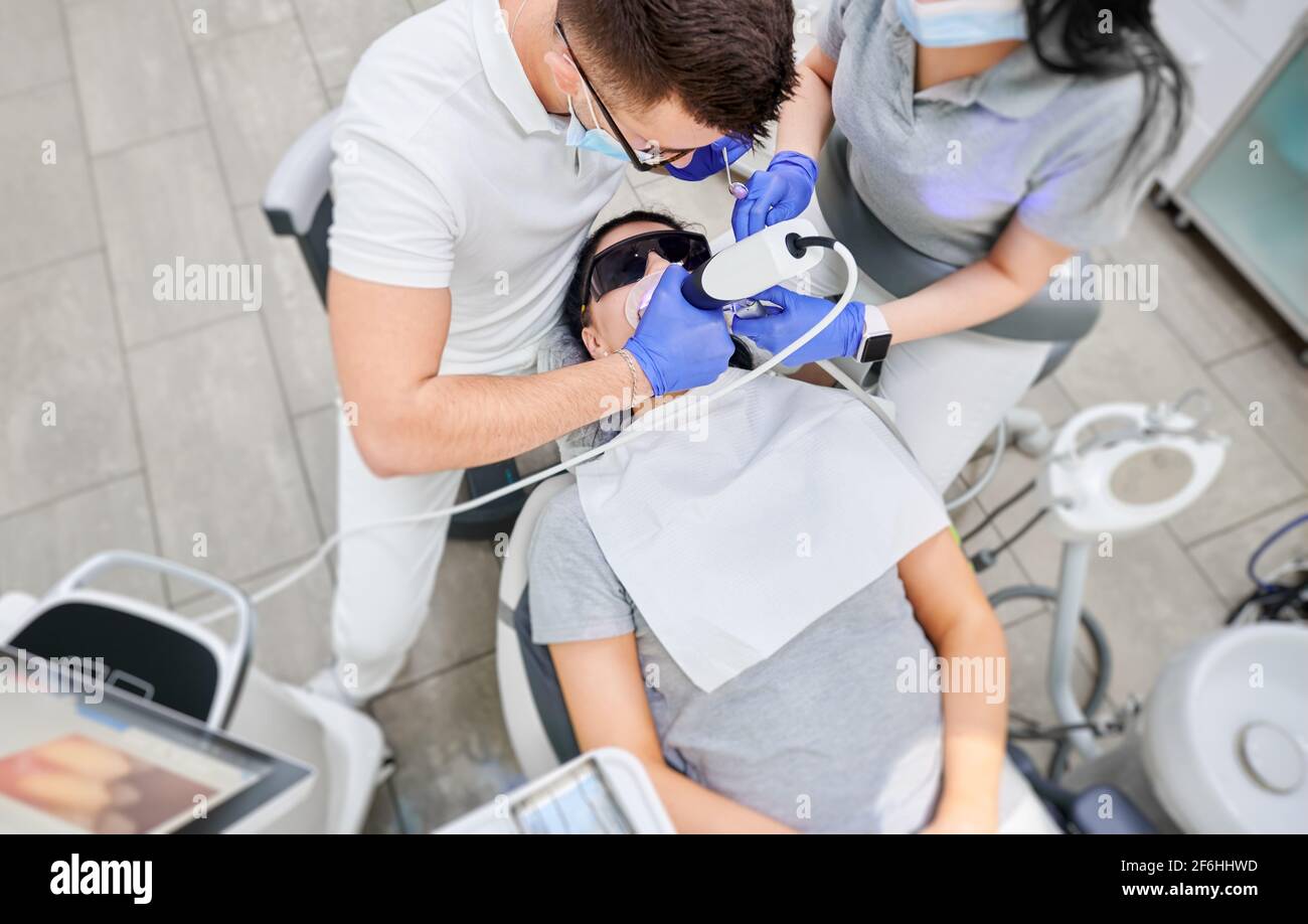Doctor and assistant examining patient teeth with intraoral scanner