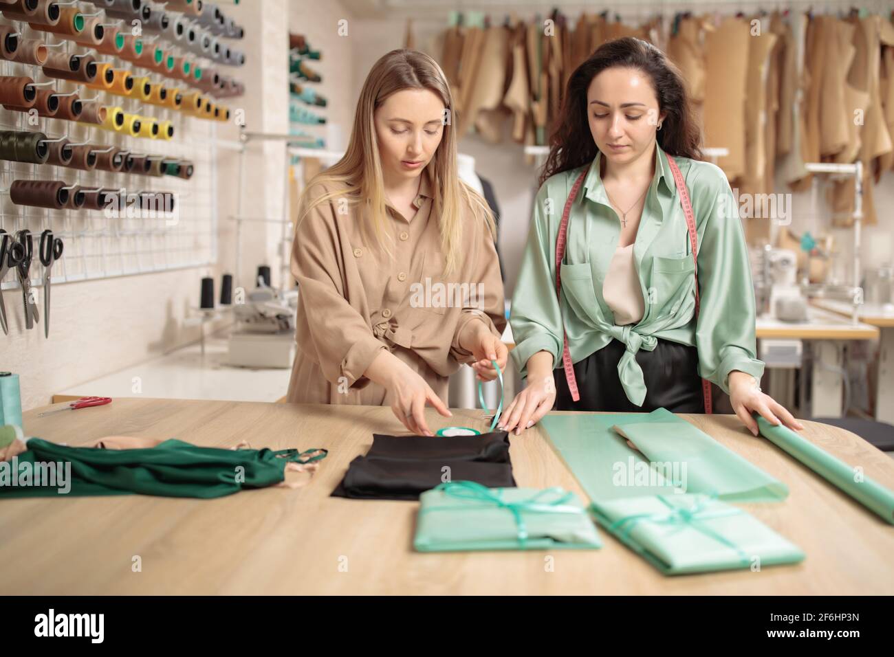 Two Young fashion designers or tailors in packing new clothes in before delivering in workshop studio Stock Photo