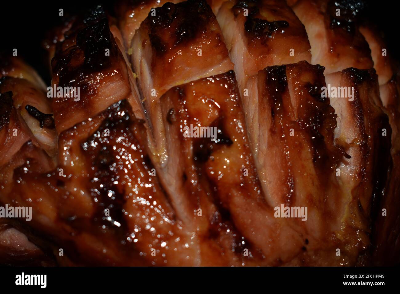 a closeup of a leg of ham coming out of the oven after being slow-roasted and infused with citrus flavoururing Stock Photo