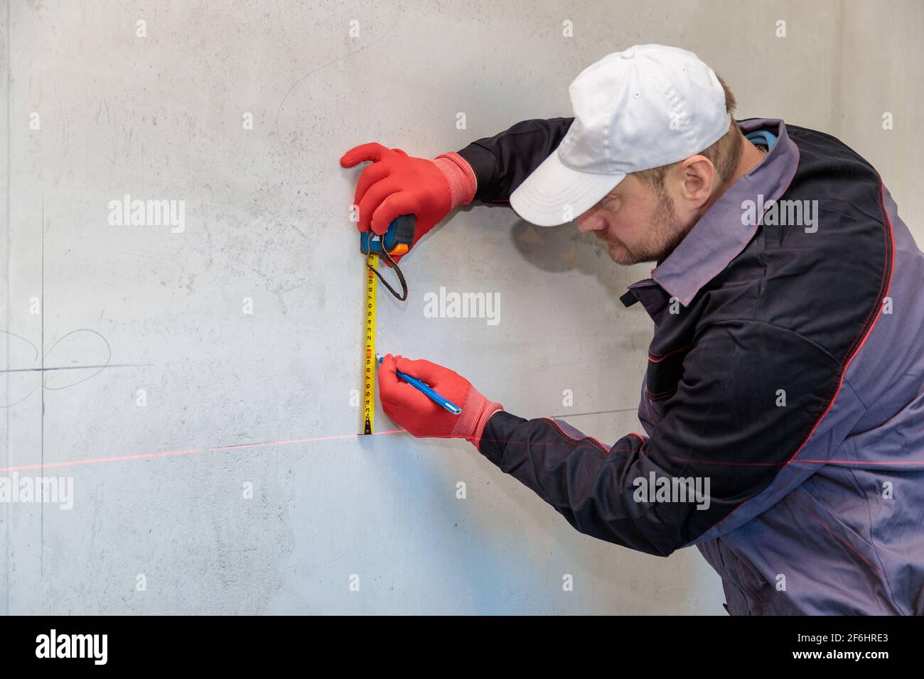 A man, an electrician marks out with a pencil, tape measure and a