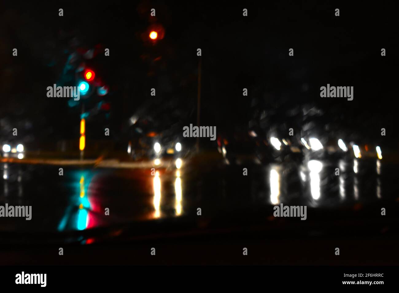 traffic lights and car lights reflecting onto a flooded road during the rain. Taken during floods in Sydney during March 2021. Stock Photo