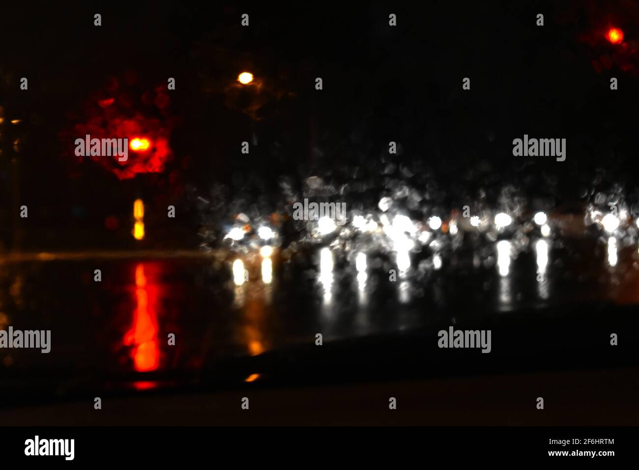 cars stopped at traffic lights with raindrops on the glass and reflections on the flooded road. Taken during floods in Sydney during March 2021. Stock Photo