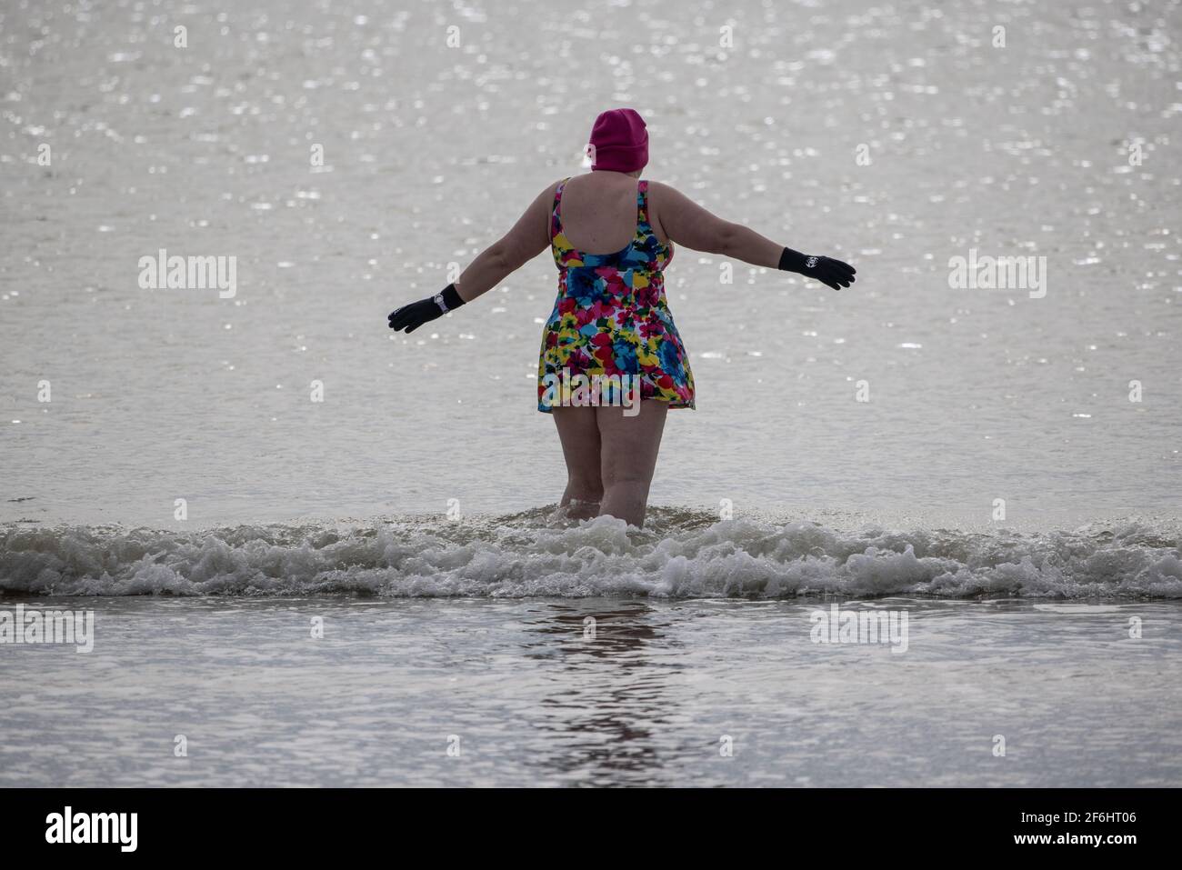 An early morning swimmer enjoys a moderately sunny morning at Felpham, along the West Sussex Coastline, England, United Kingdom Stock Photo