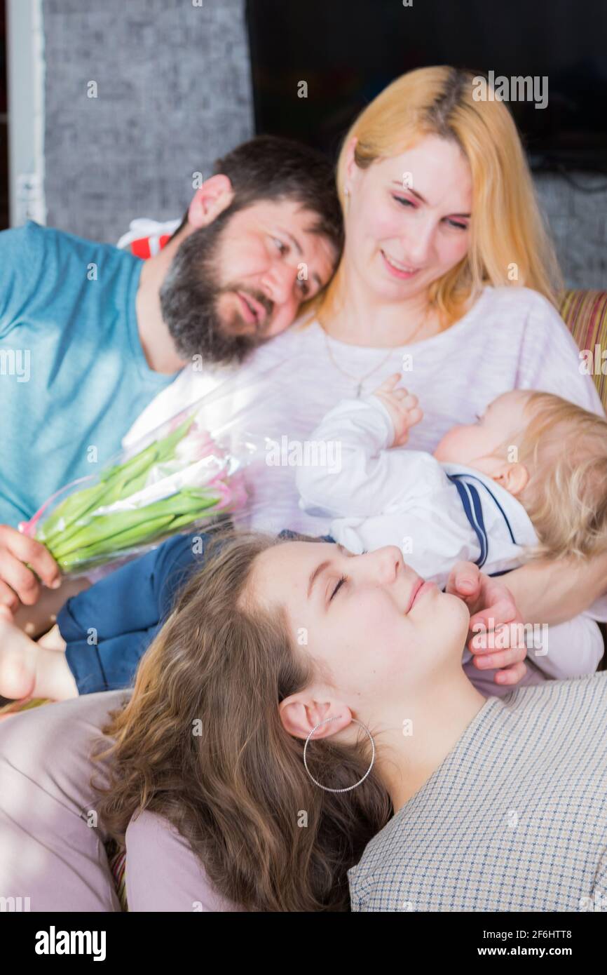 Dad with children congratulate mom on the holiday, mother's day. Have fun, laugh and give flowers Stock Photo