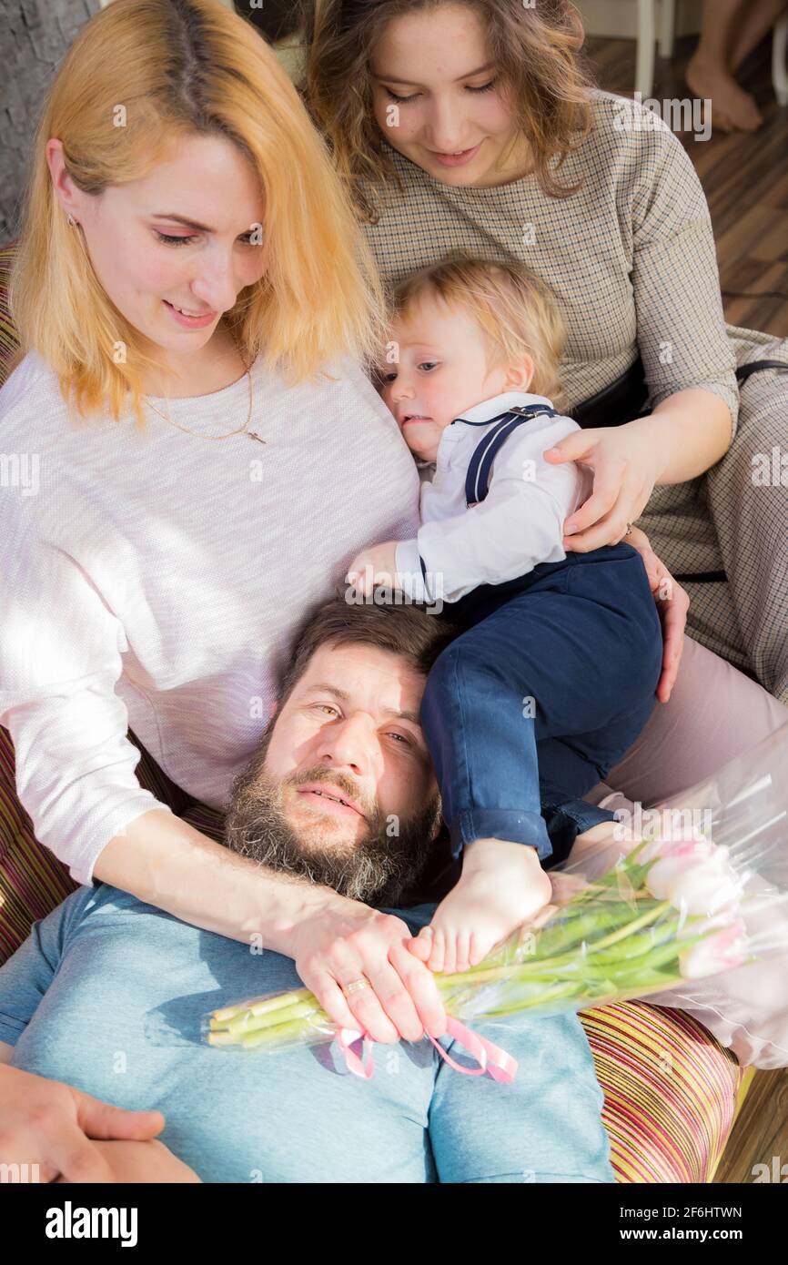 Dad with children congratulate mom on the holiday, mother's day. Have fun, laugh and give flowers Stock Photo