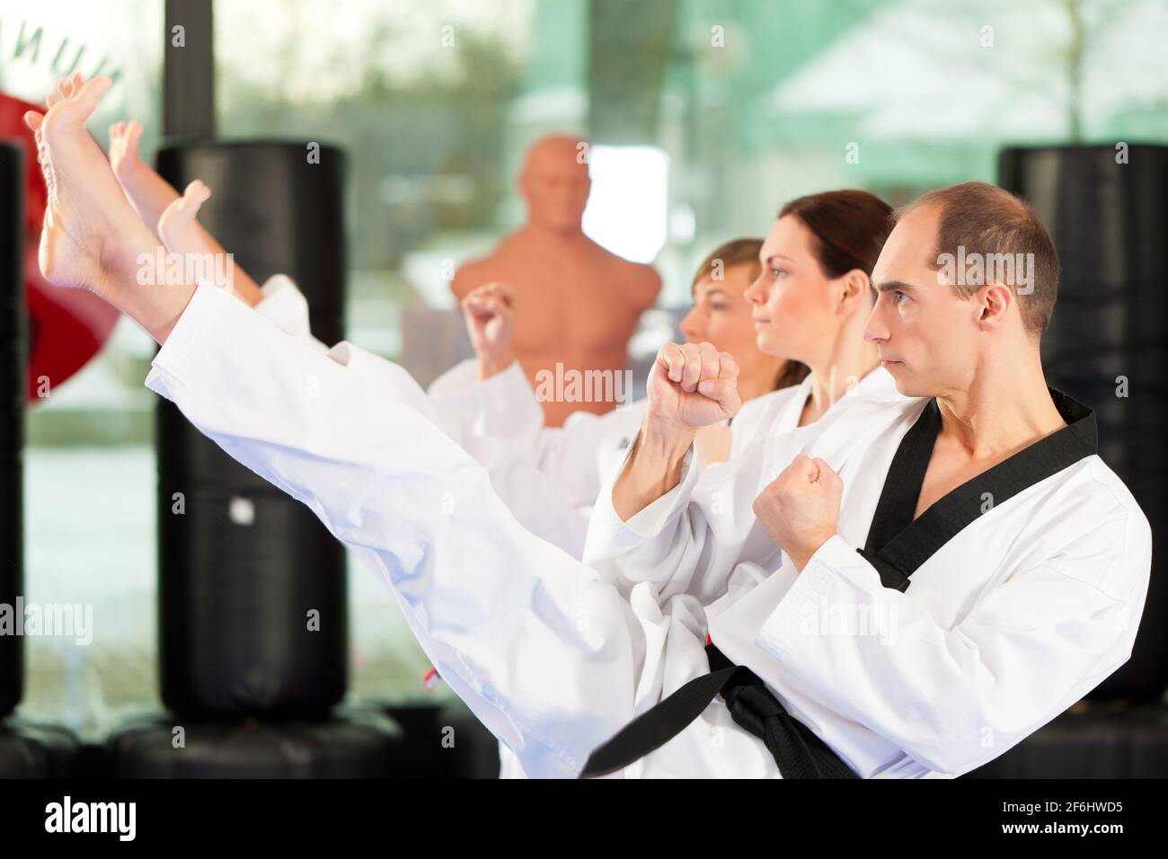 Leute im Fitnessstudio beim Training von Kampfsport, es geht um Taekwondo, der Trainer hat den schwarzen Gürtel Stock Photo