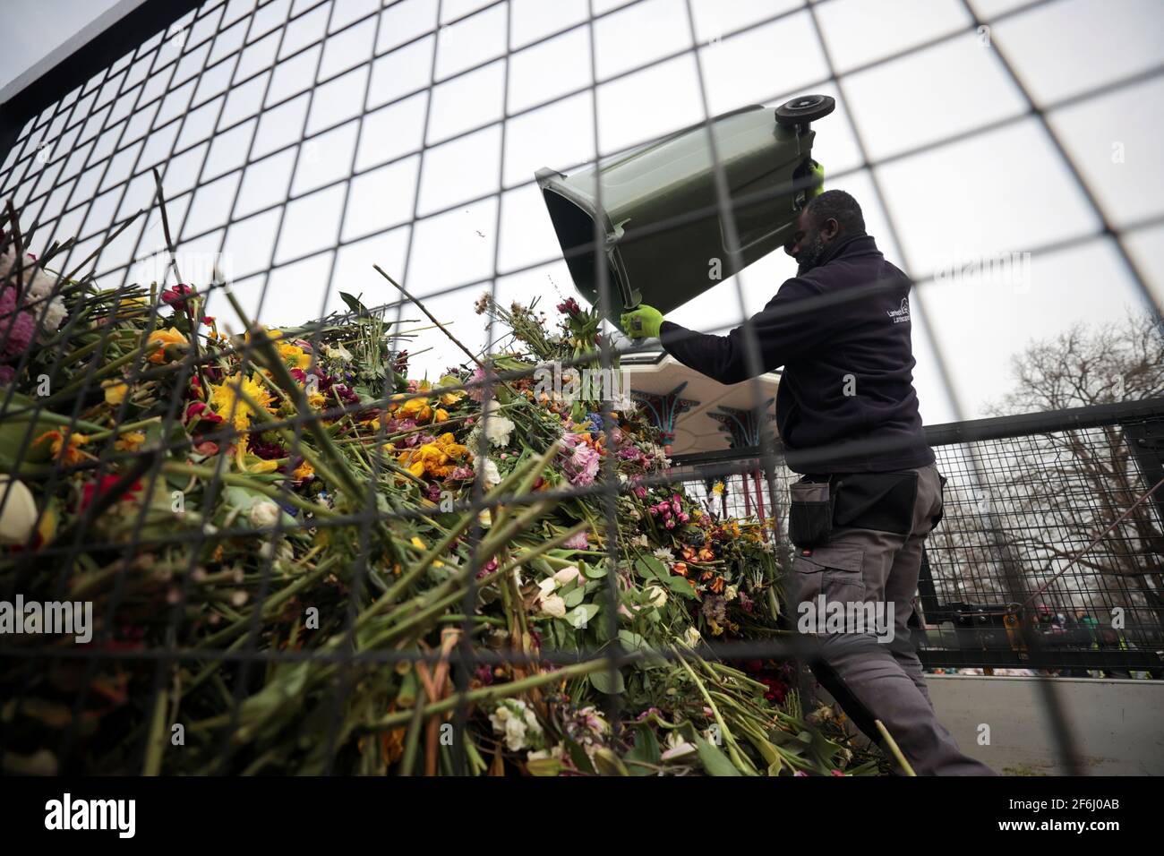 A council worker clears floral tributes from a makeshift memorial for the murdered Sarah Everard from the Clapham Common Bandstand in London, Britain, April 1, 2021. REUTERS/Hannah McKay Stock Photo