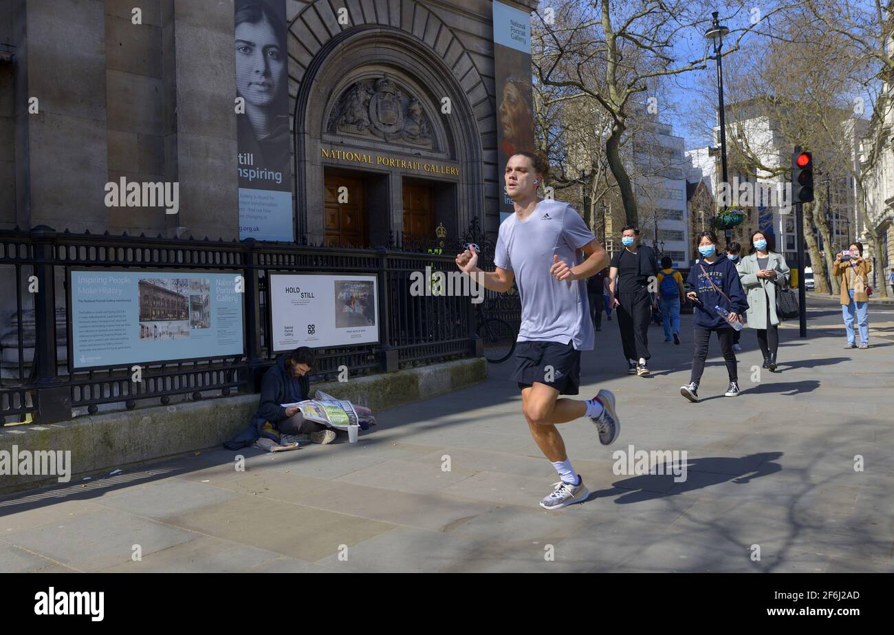 London, England, UK. Jogger running past the National Portrait Gallery in St Martin's Place Stock Photo