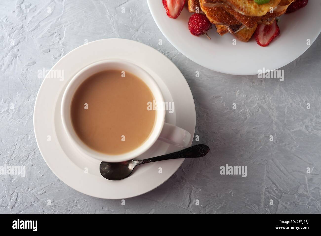 A cup of coffee with cream and French toast with cinnamon and strawberries. Morning breakfast Stock Photo