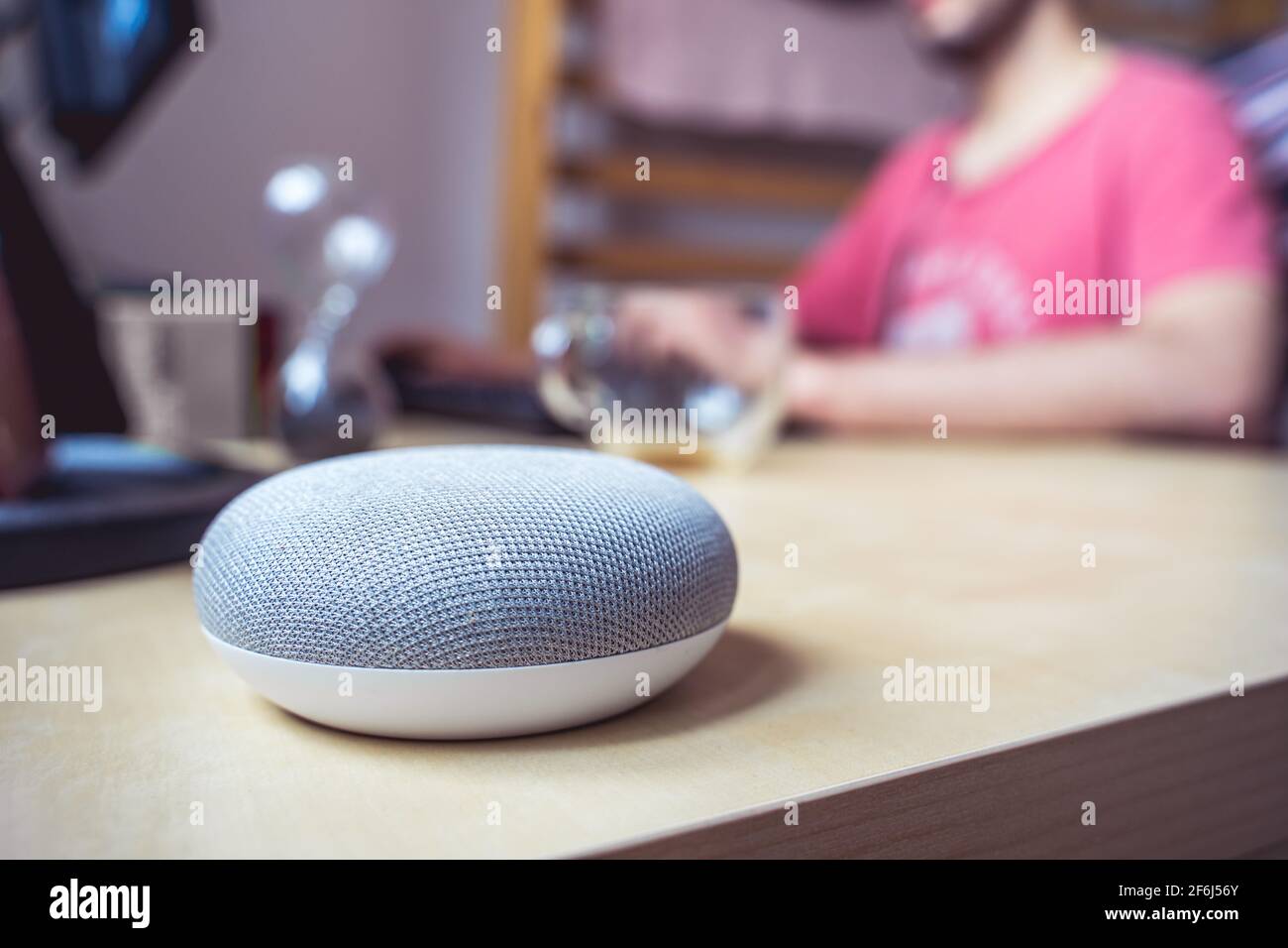 voice controlled smart speaker in a interior. male working in background Stock Photo