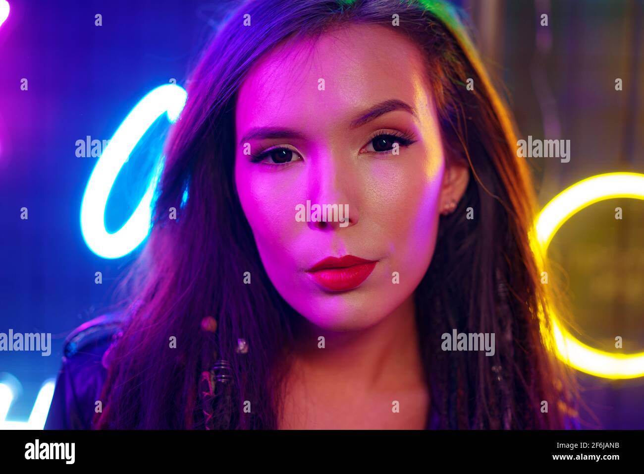 Portrait of a young attractive female standing near neon lamps at night Stock Photo