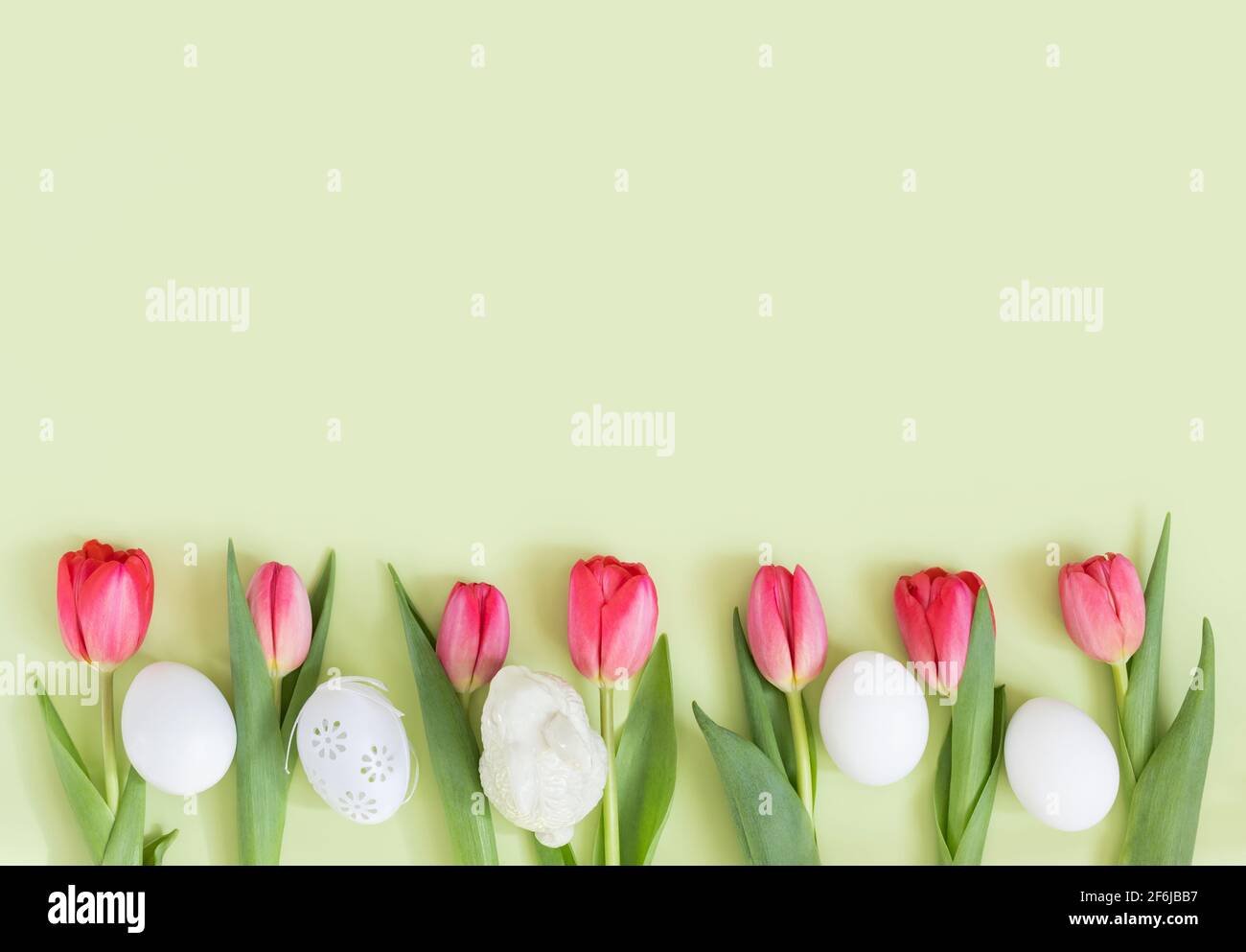 Easter border with pink tulips, white eggs and a rabbit on a green ...