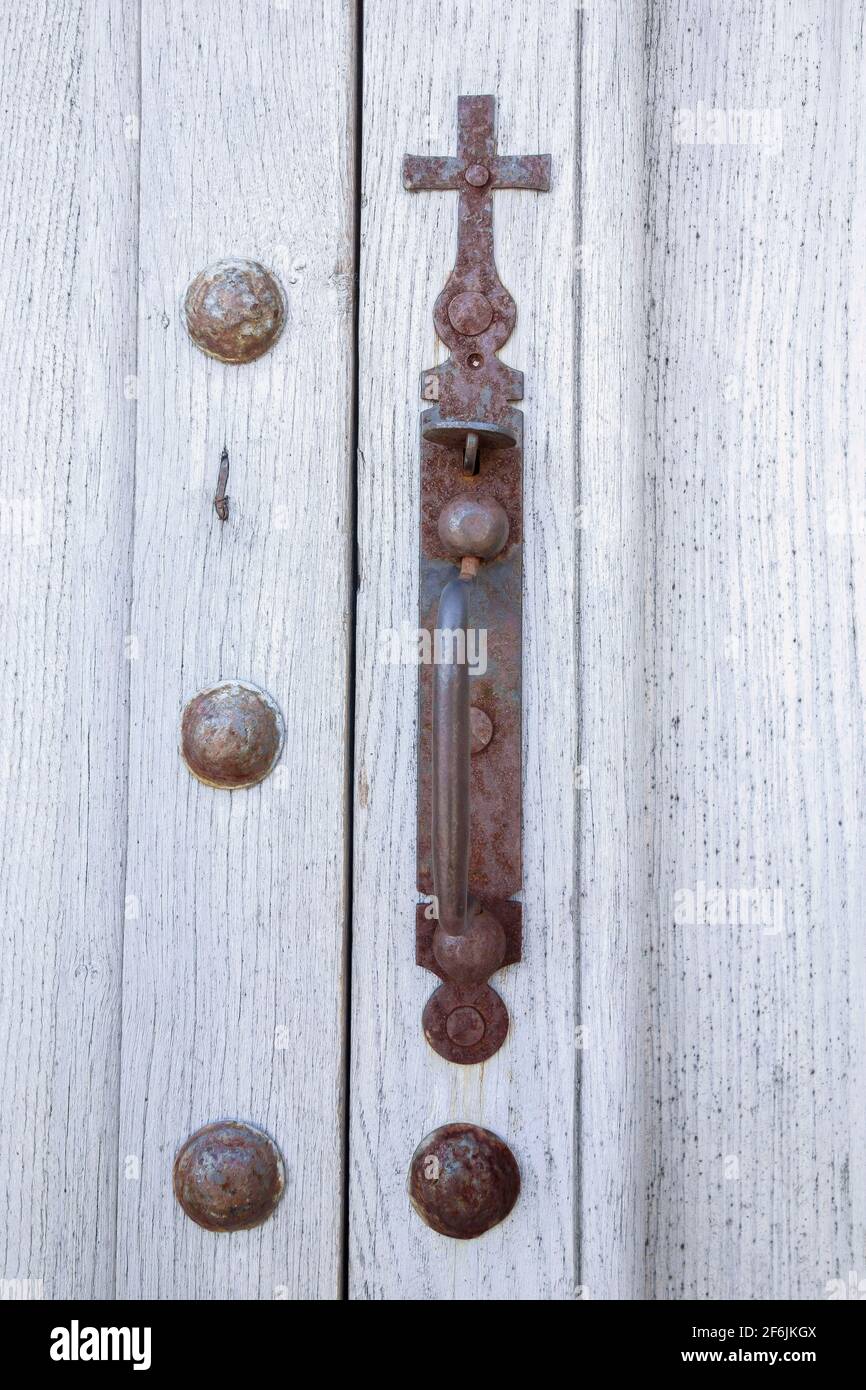 Old wooden church door, handle surmounted by a cross, symbolic religious image, Christianity. Saint-Christol church, La Couvertoirade, Aveyron, France Stock Photo