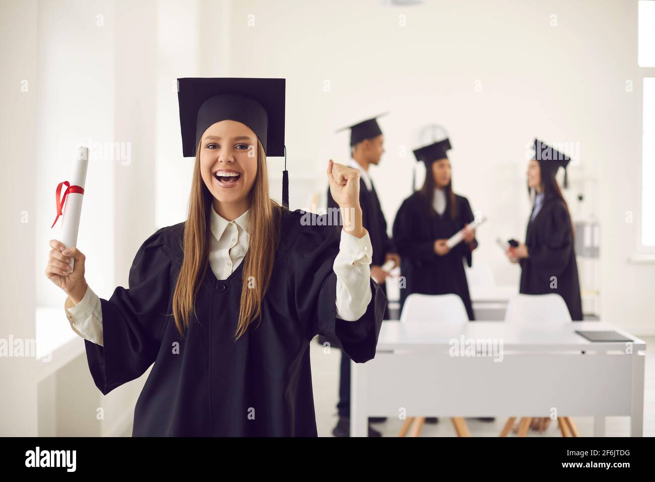 Excited student holding her diploma and celebrating college or university graduation Stock Photo