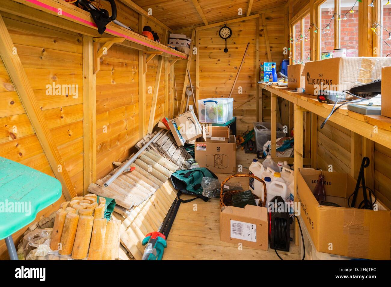 Interior of a half empty but messy wooden garden shed or tool shed in the UK. Stock Photo