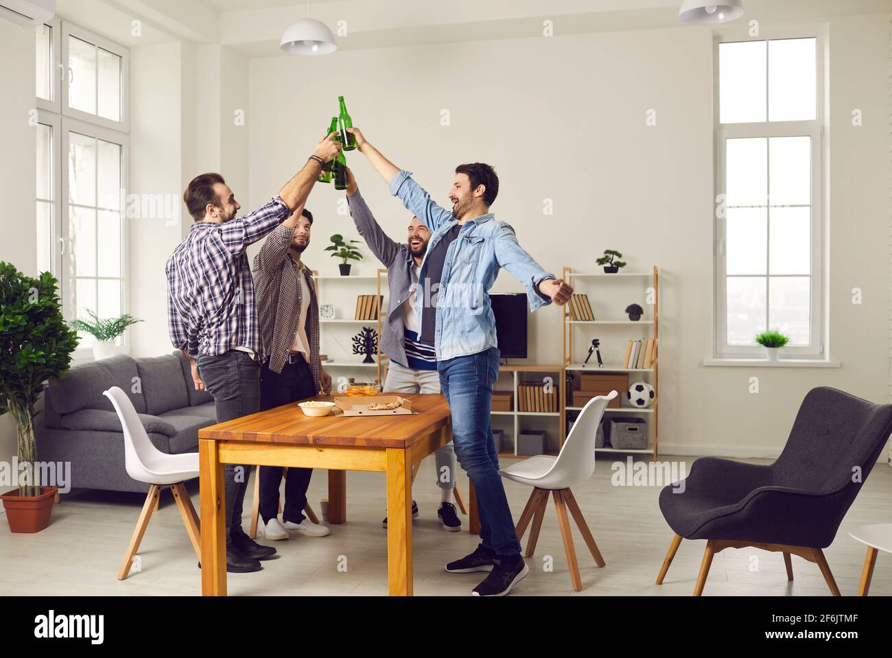 Bunch of happy friends drinking beer, eating pizza and enjoying good time together Stock Photo