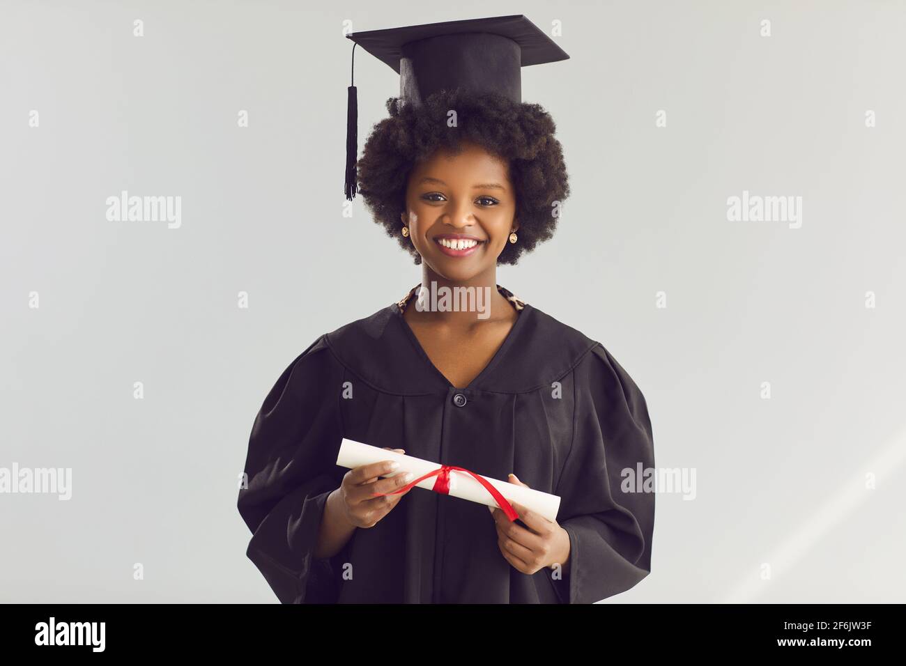 African american woman in academic hat and gown with diploma studio headshot Stock Photo
