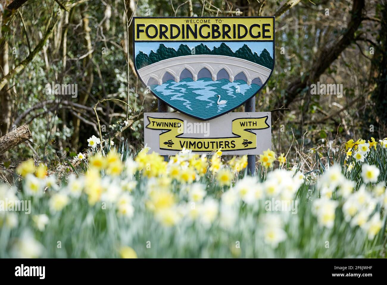 Fordingbridge, UK - 22 Mar 2021: A sign for the Hampshire town of Fordingbridge is surrounded by daffodil flowers as Spring approaches. Stock Photo