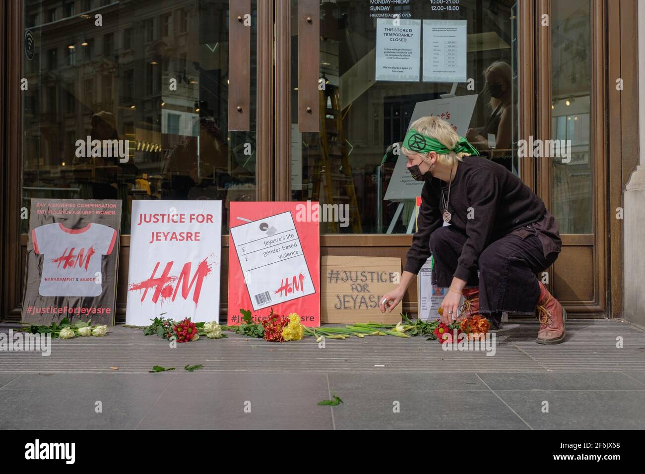 London, UK. April 1, 2021. Extinction rebellion protesters drop flower in  front of H&M in memory of JEYASRE KATHIRAVEL an Indian woman who was raped  and murdered while working in exploitative garment