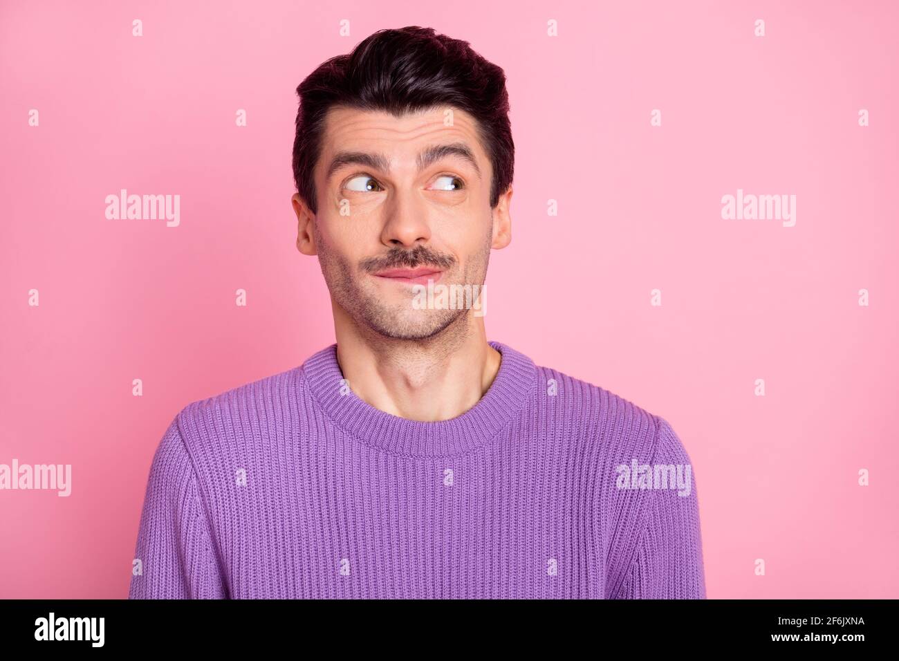 Photo of funny tricky young guy wear violet sweater looking empty space isolated pastel pink color background Stock Photo